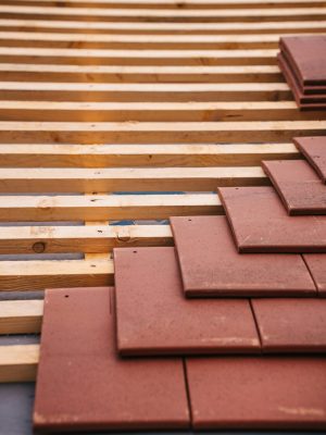 Red roofing tiles and wooden framework in progress on a building roof.